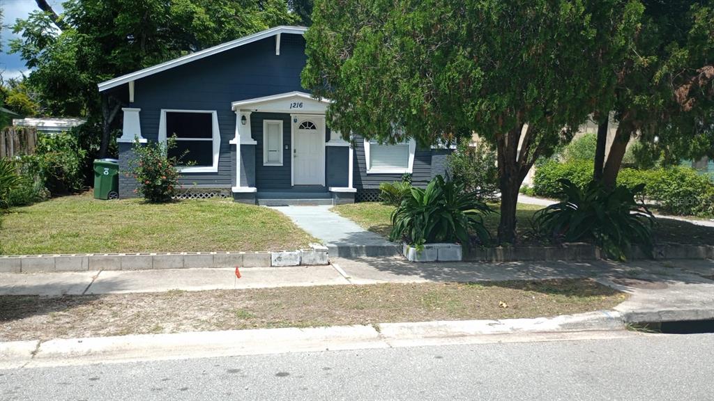 a view of a yard in front of a house with large tree