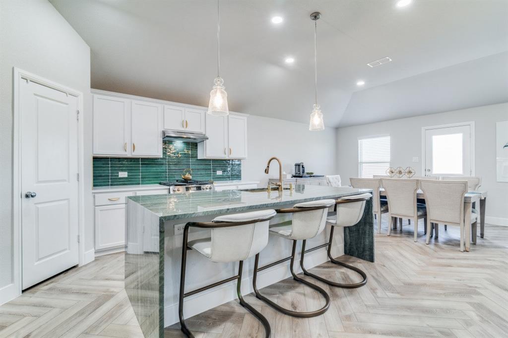 a kitchen with stainless steel appliances granite countertop a table chairs sink and cabinets