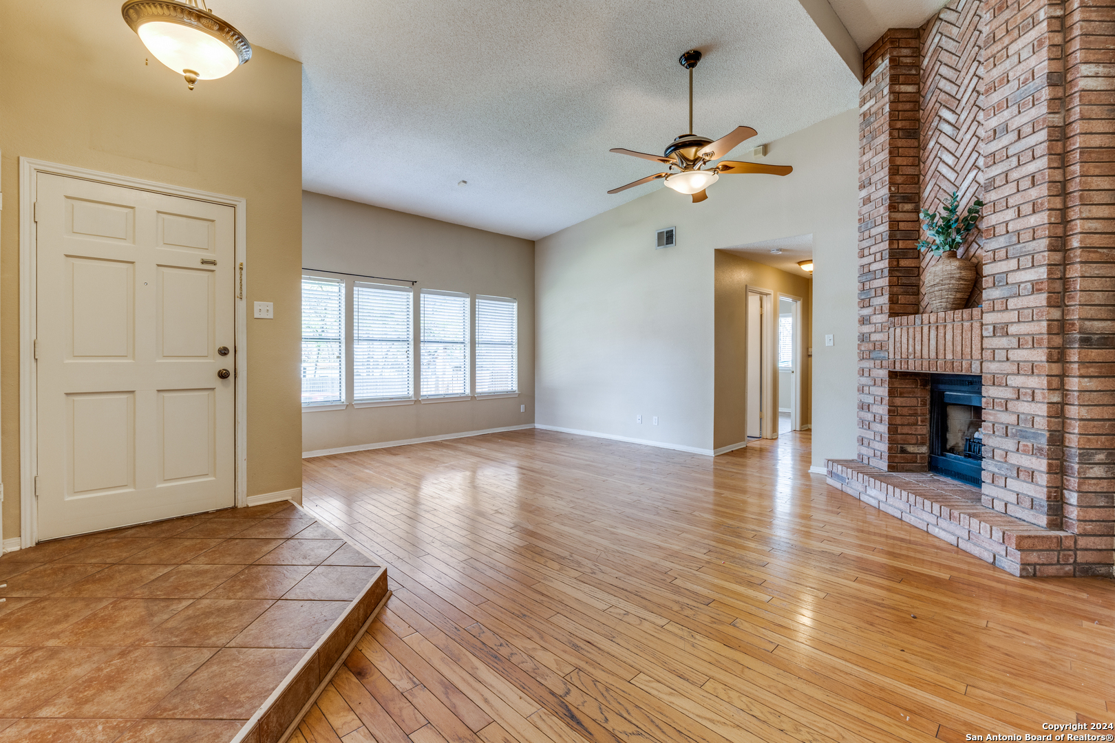 an empty room with wooden floor fireplace and windows