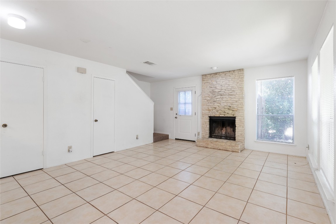 a view of an empty room with a fireplace and a window