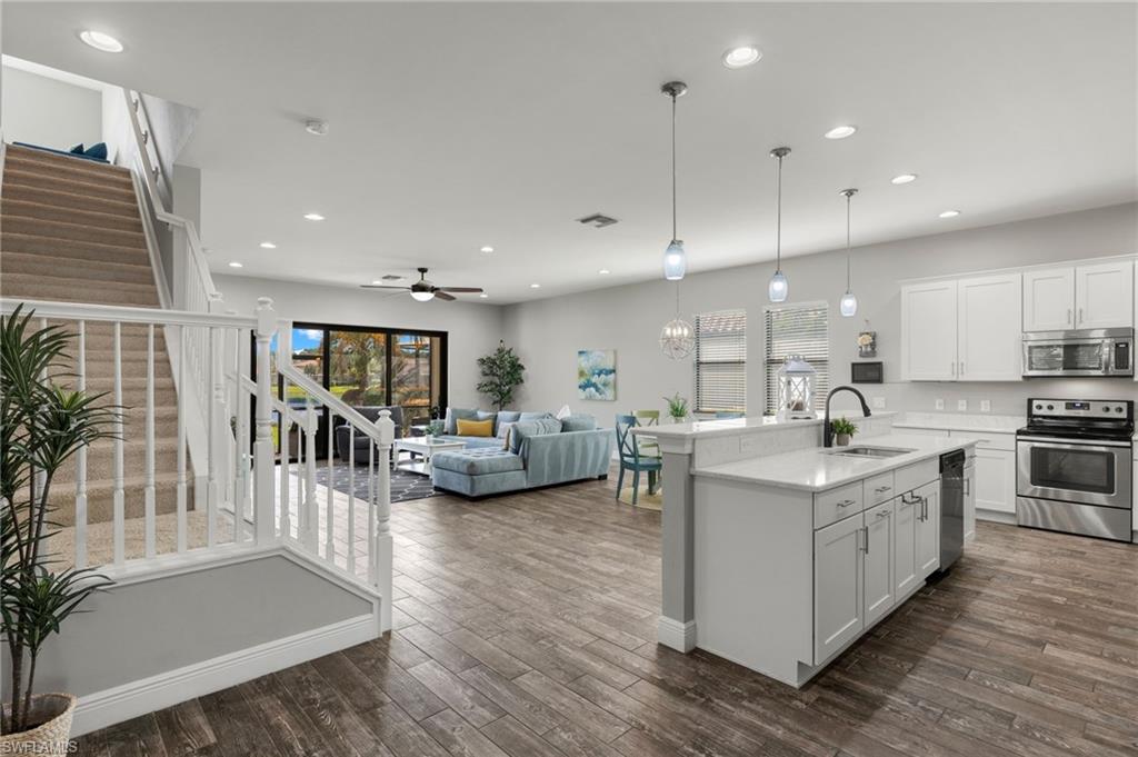 a large white kitchen with lots of counter space a sink and stainless steel appliances