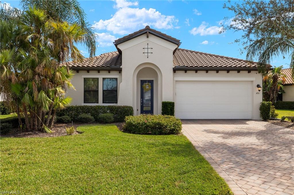 Mediterranean / spanish home featuring a front lawn and a garage.