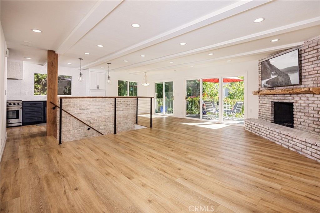 an empty room with wooden floor fireplace and windows