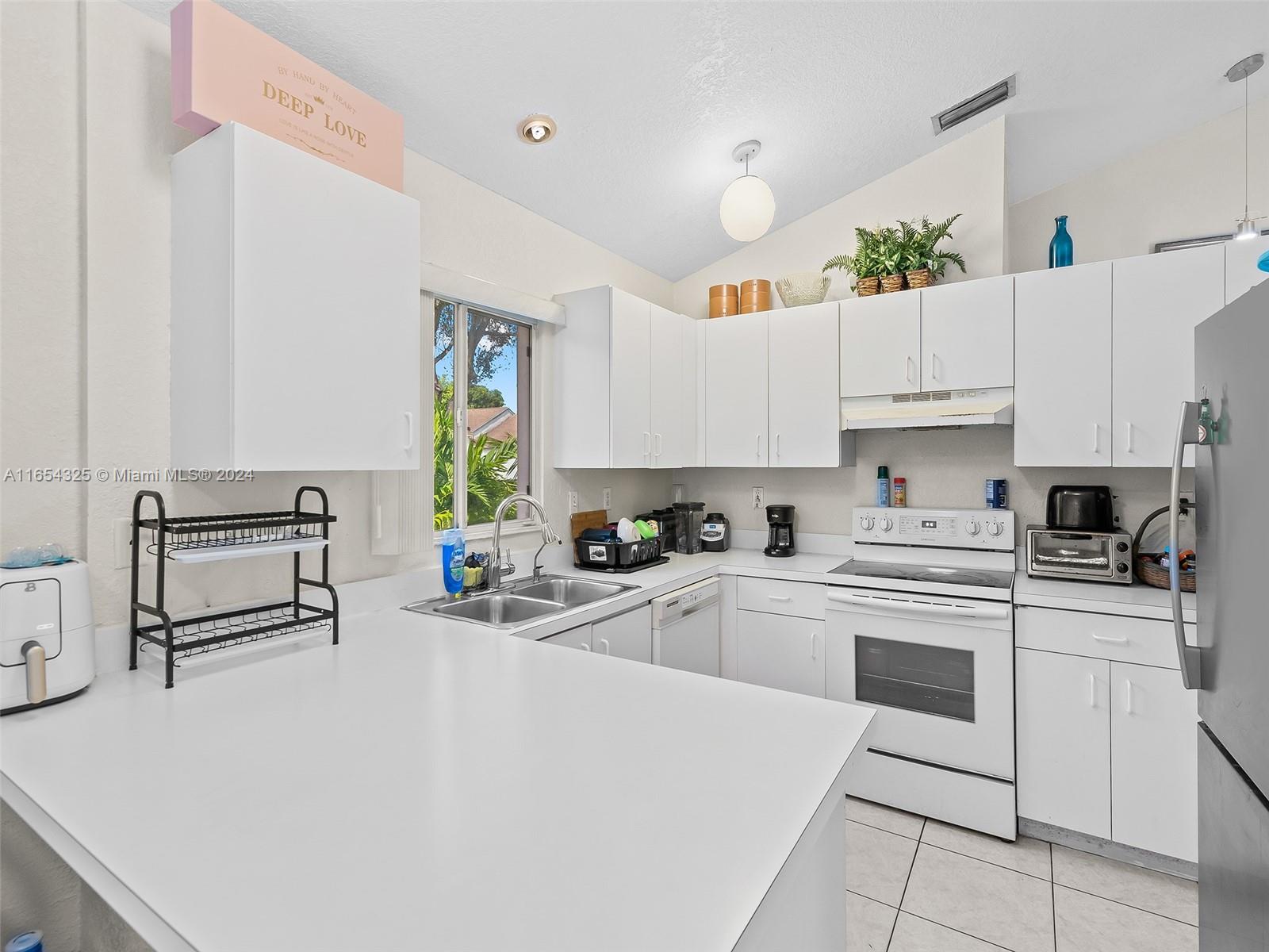 a kitchen with granite countertop a stove a sink and white cabinets with wooden floor