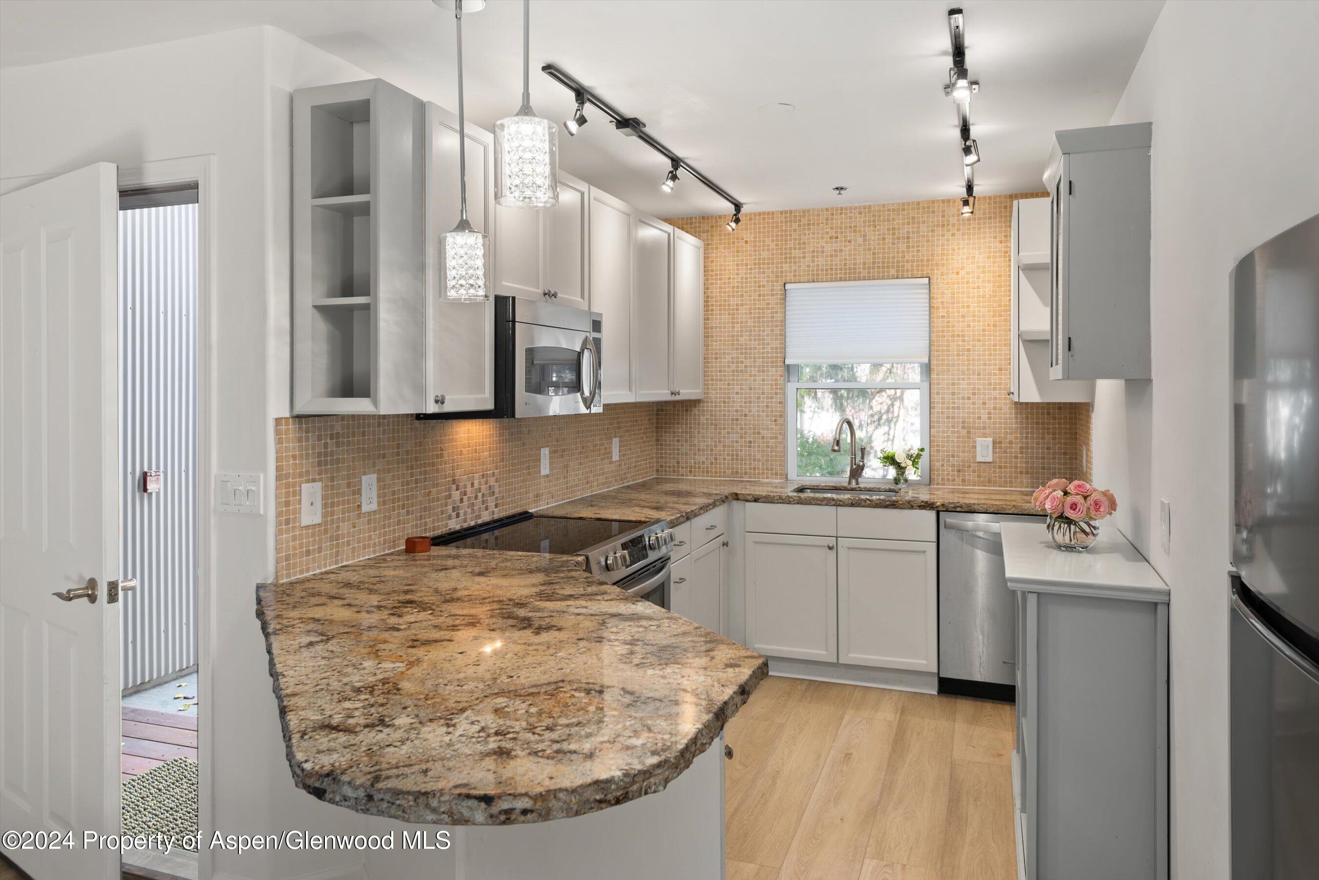 a kitchen with stainless steel appliances granite countertop a sink stove and refrigerator