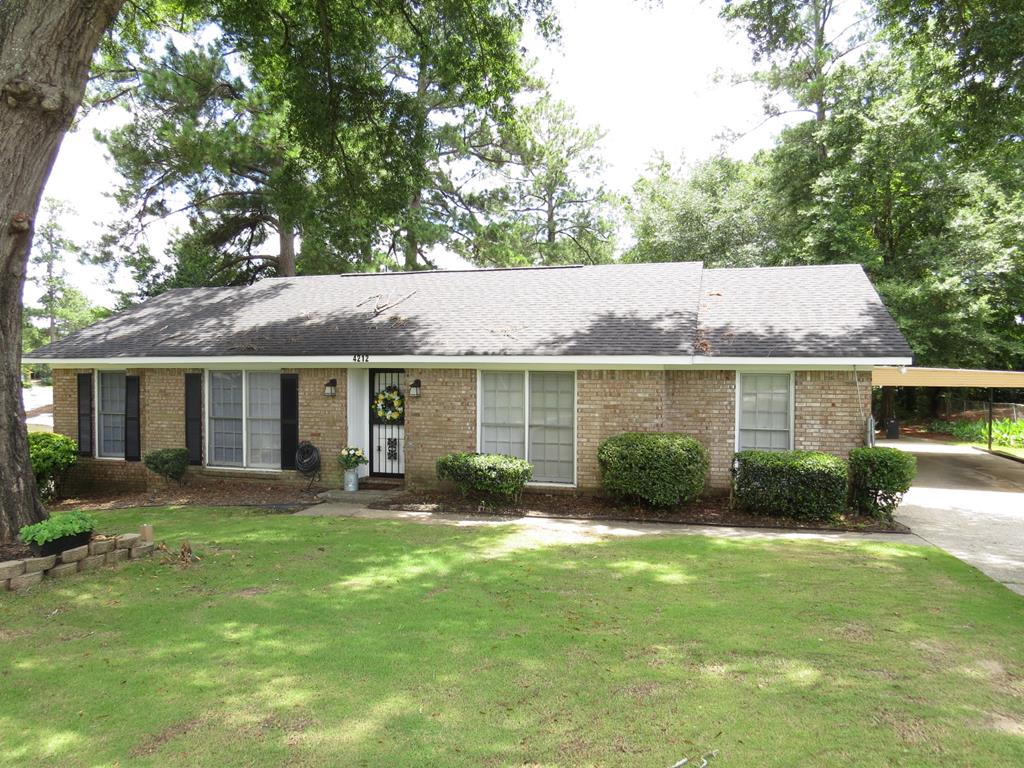 a view of a house with a yard and a large tree