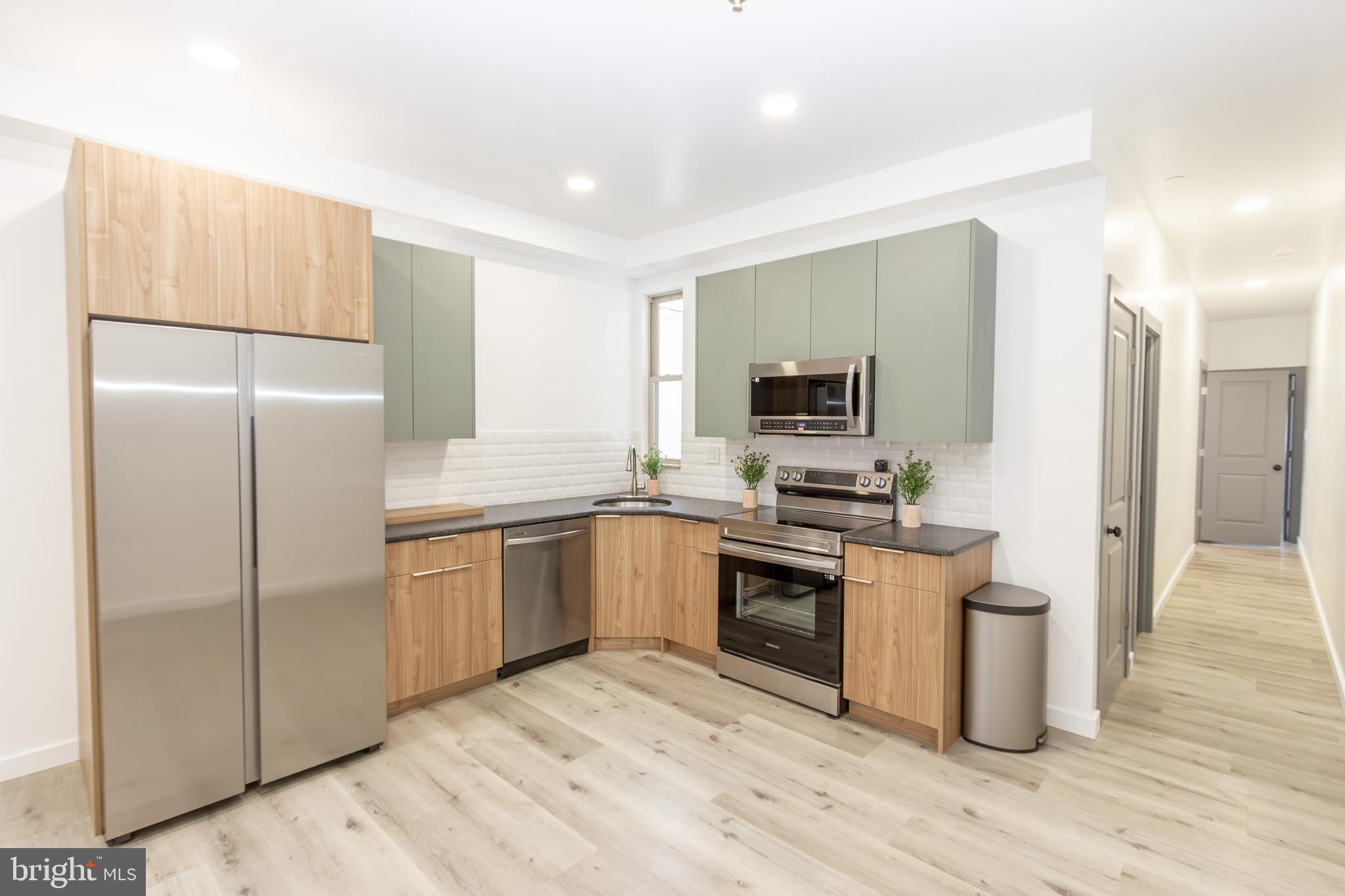 a kitchen with a refrigerator stove and wooden floor