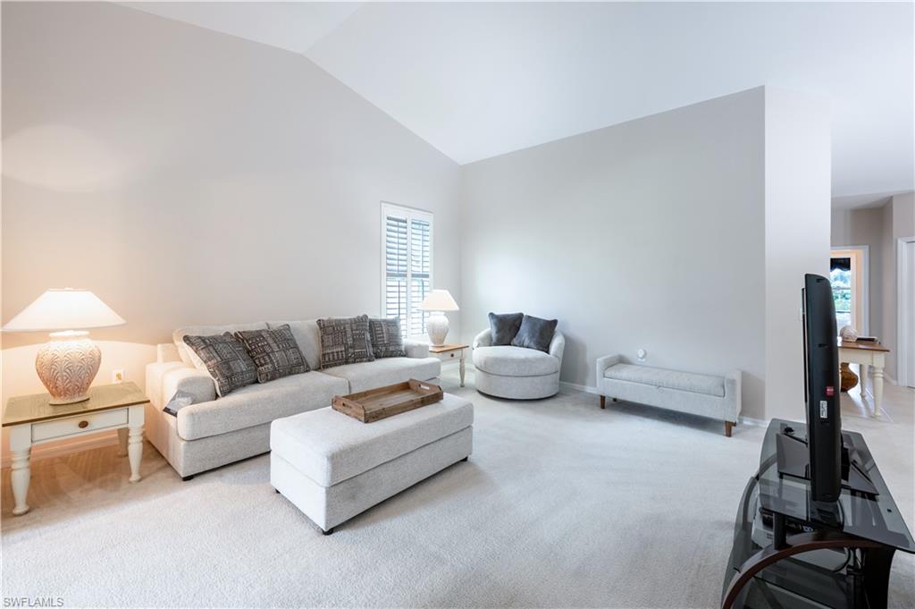 Living room with high vaulted ceiling and light carpet