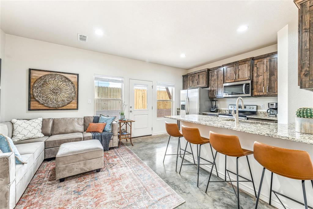 a living room with stainless steel appliances kitchen island granite countertop furniture and a wooden floor