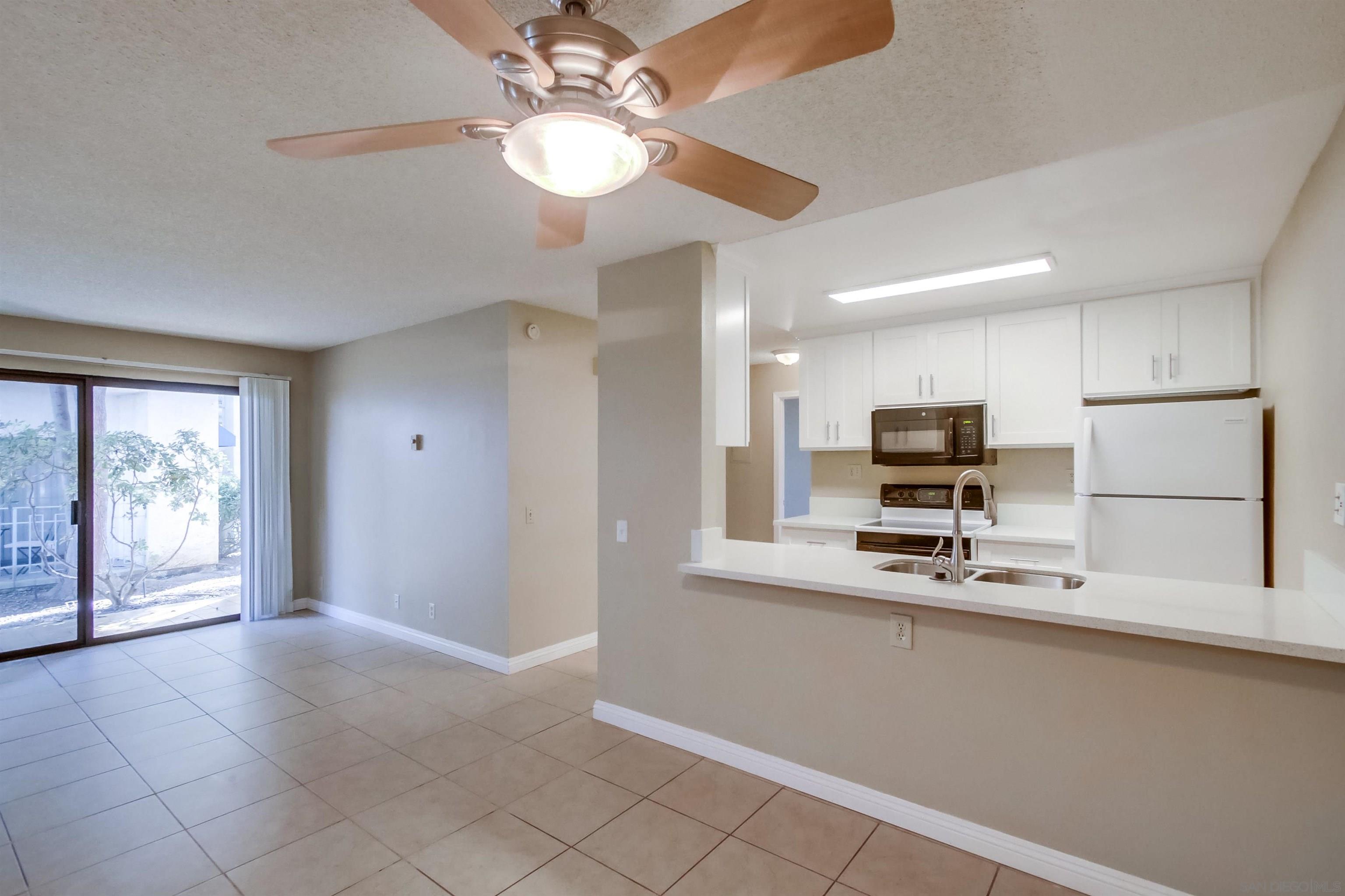 a kitchen with stainless steel appliances a sink a stove a refrigerator cabinets and living room view