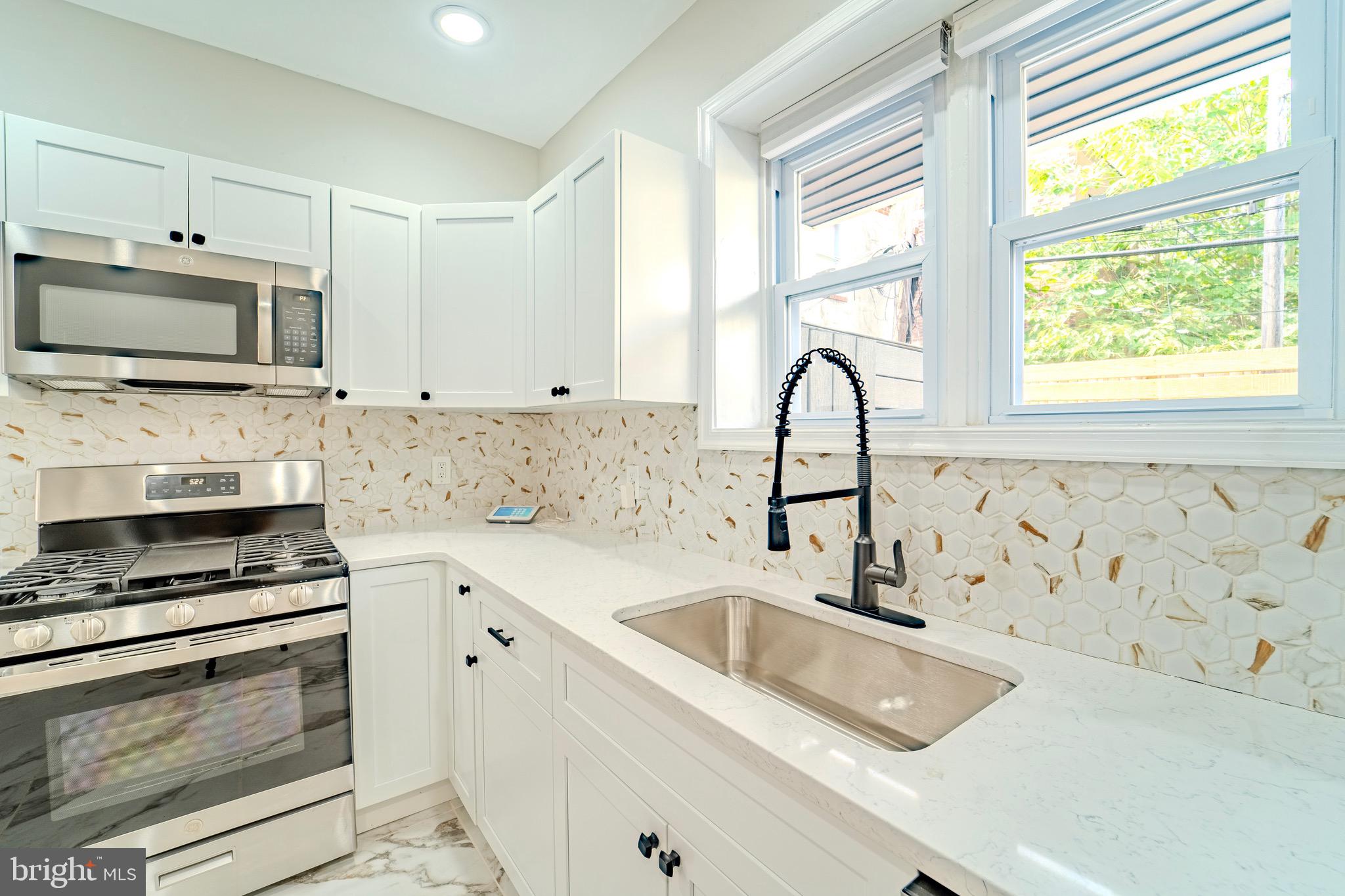 a kitchen with stainless steel appliances a stove a sink a microwave and cabinets