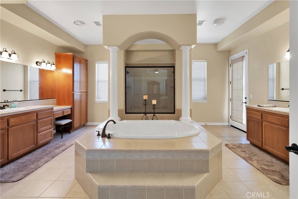 a spacious bathroom with a granite countertop tub a double vanity sink and a large mirror