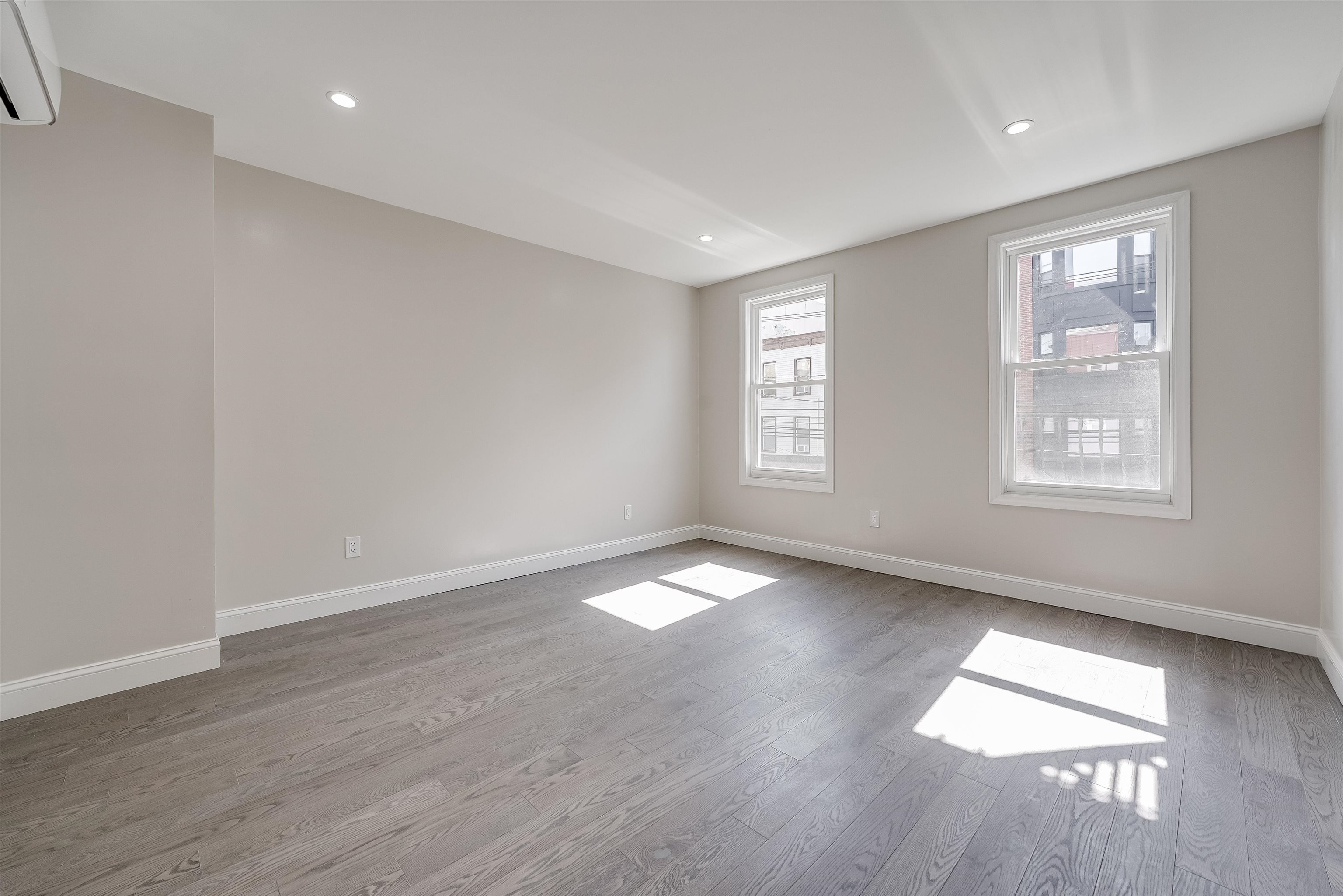 an empty room with wooden floor and windows