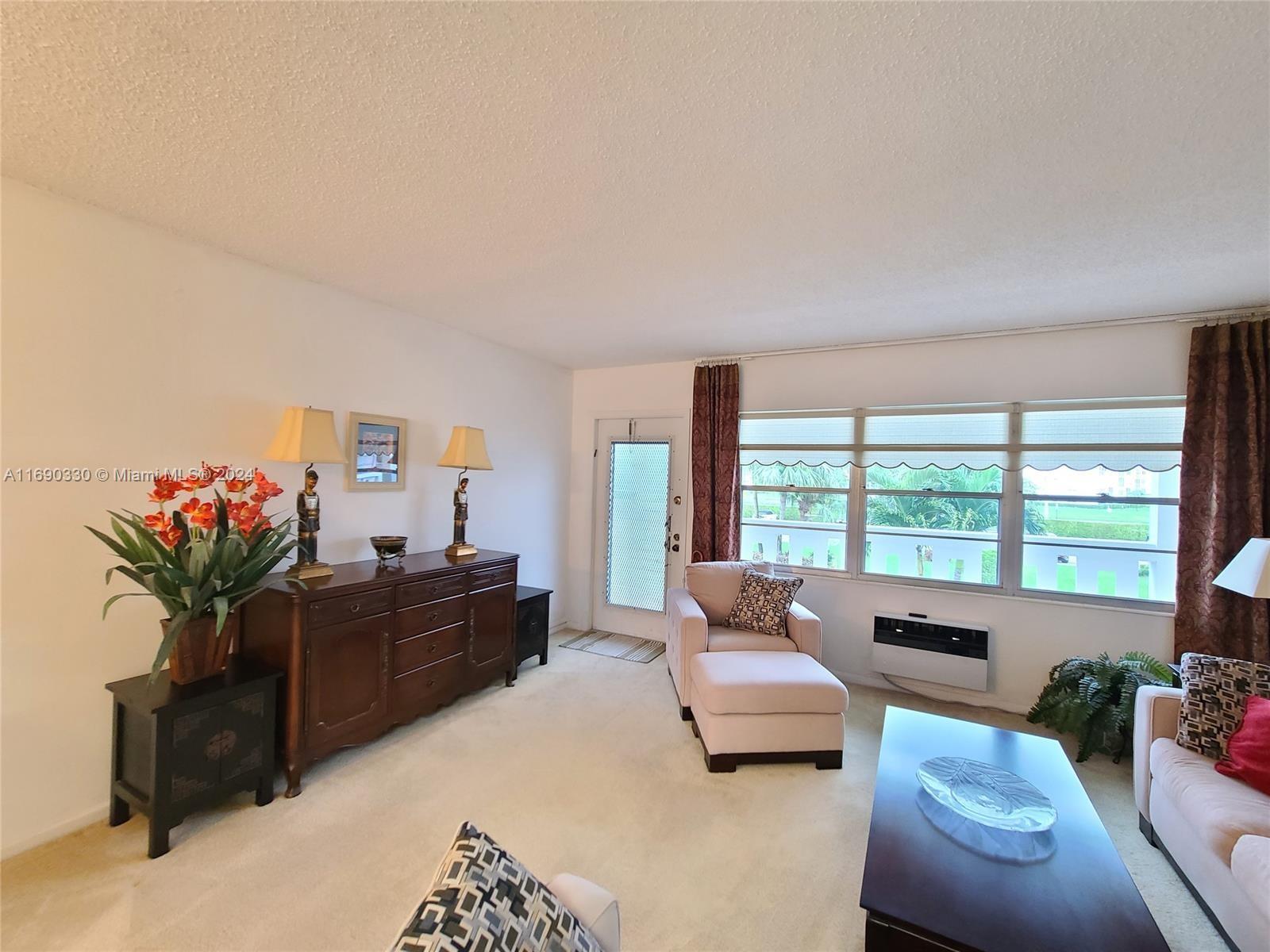 a living room with furniture large windows and flat screen tv