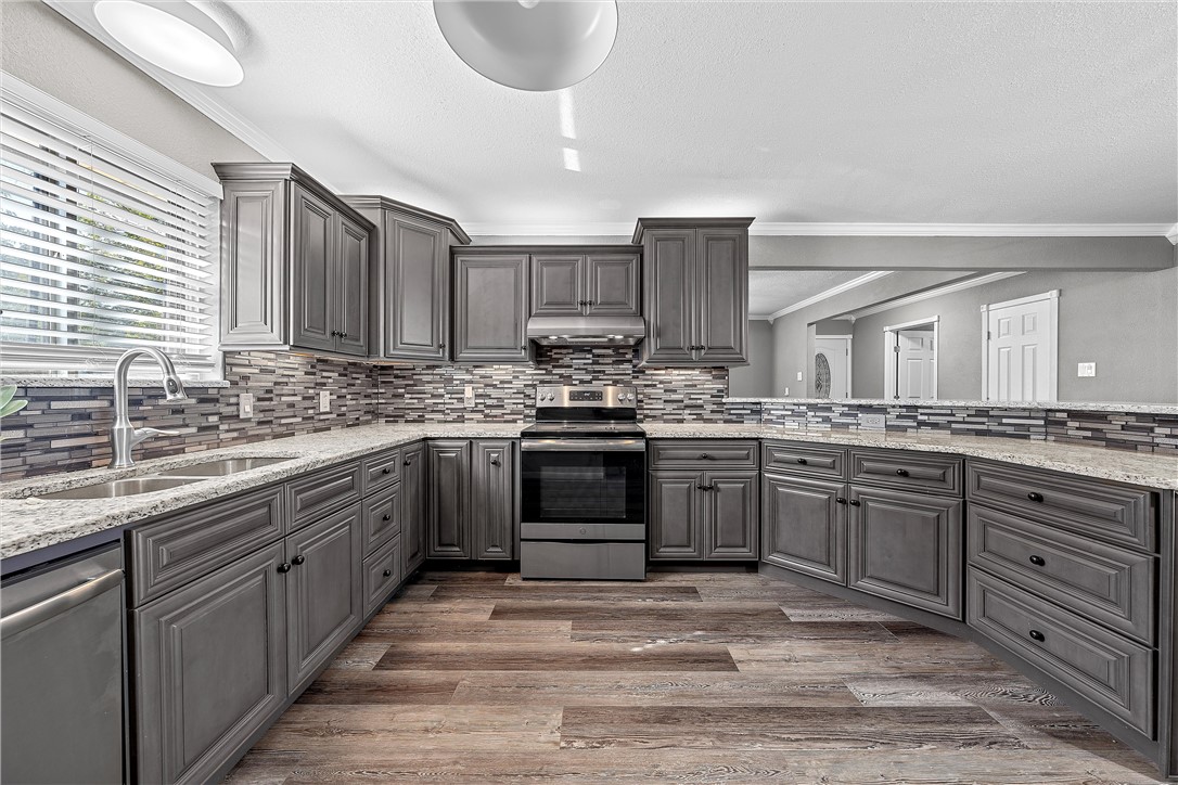 a kitchen with granite countertop a sink stainless steel appliances and cabinets