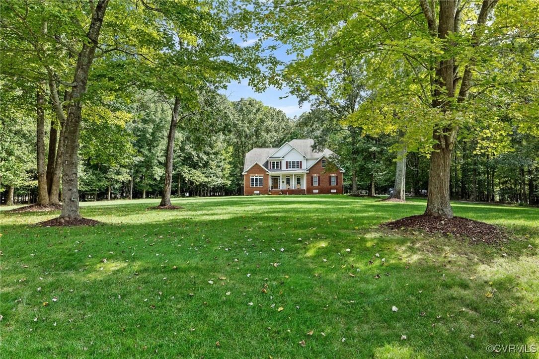 a view of a white house in front of a big yard with large trees