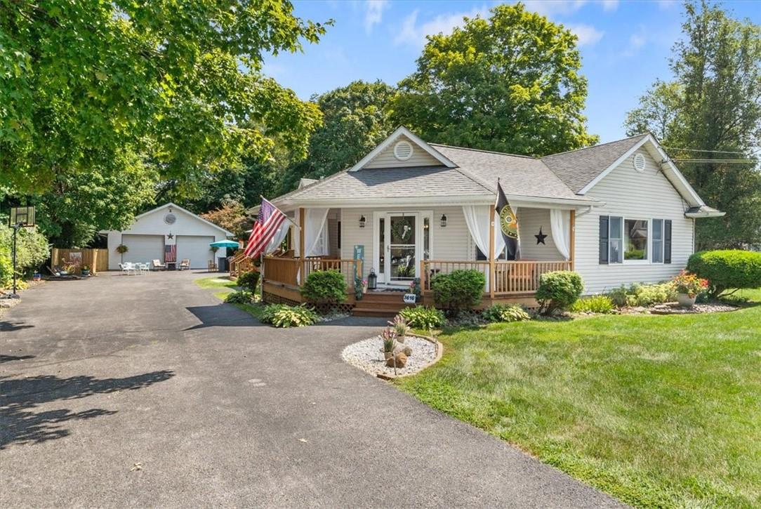 View of front of house with a covered porch, an oversized garage, a long expanded driveway and a lush front yard.