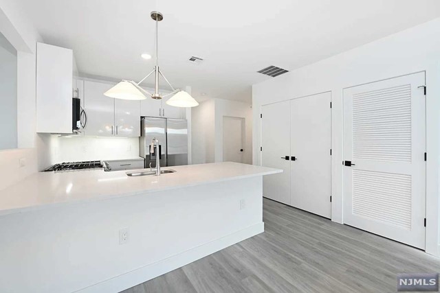 a large white kitchen with wooden floor