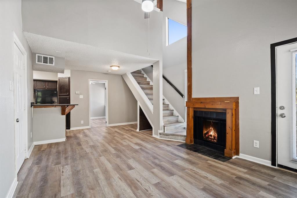 a view of an empty room with wooden floor fireplace and a window