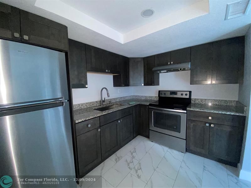 a kitchen with stainless steel appliances granite countertop a refrigerator and a sink