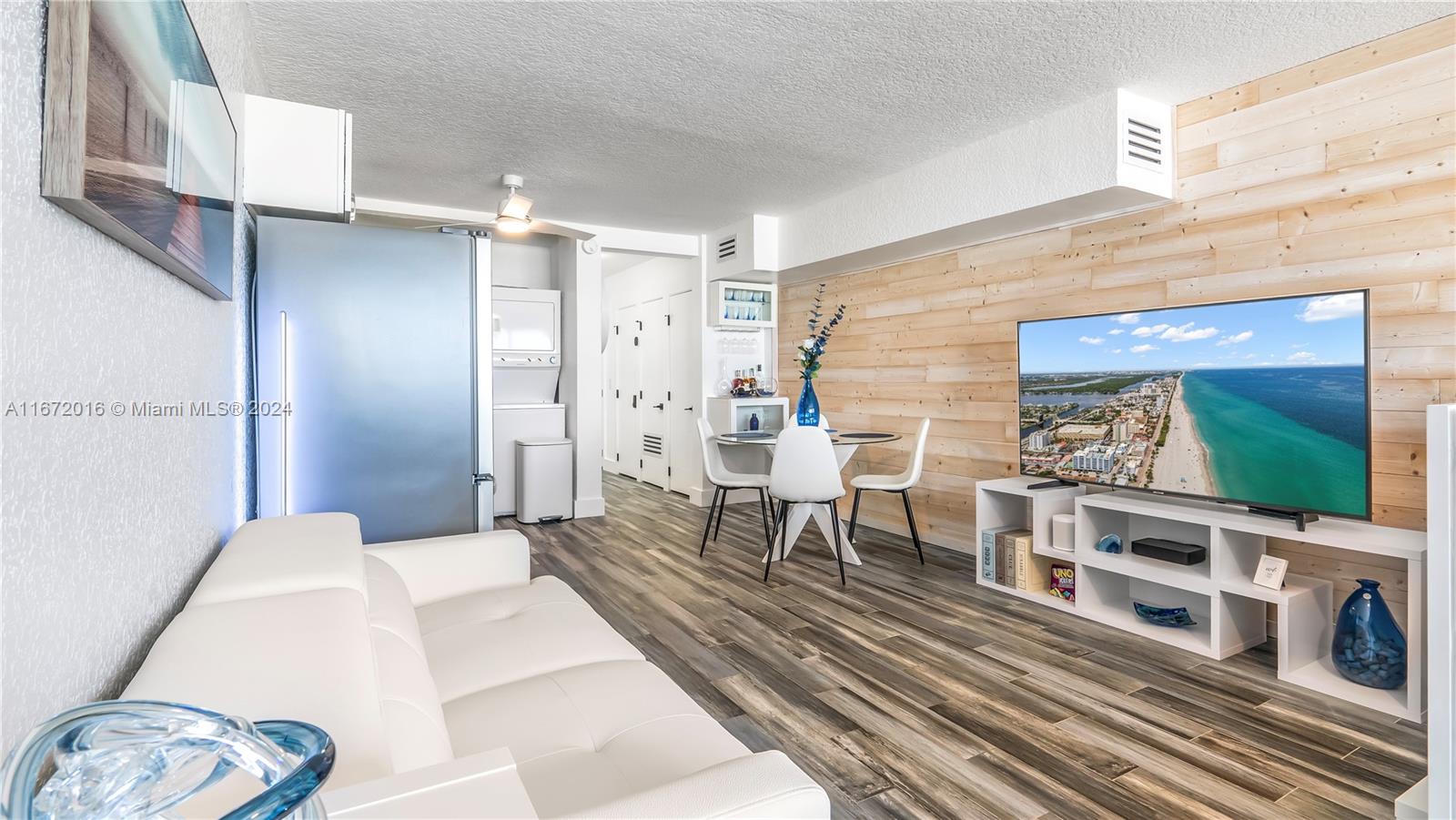 a living room with stainless steel appliances furniture a rug and a flat screen tv