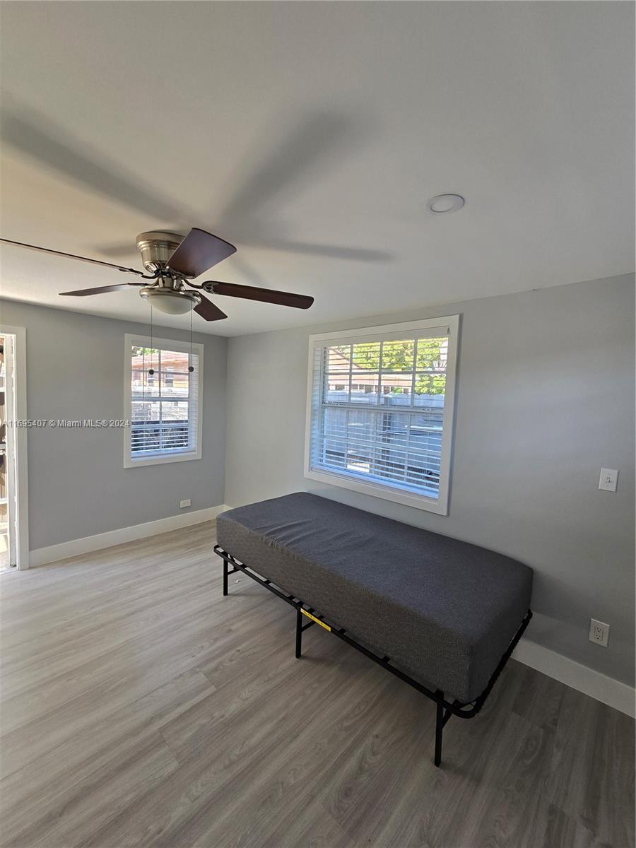 a living room with hardwood floor windows and a ceiling fan