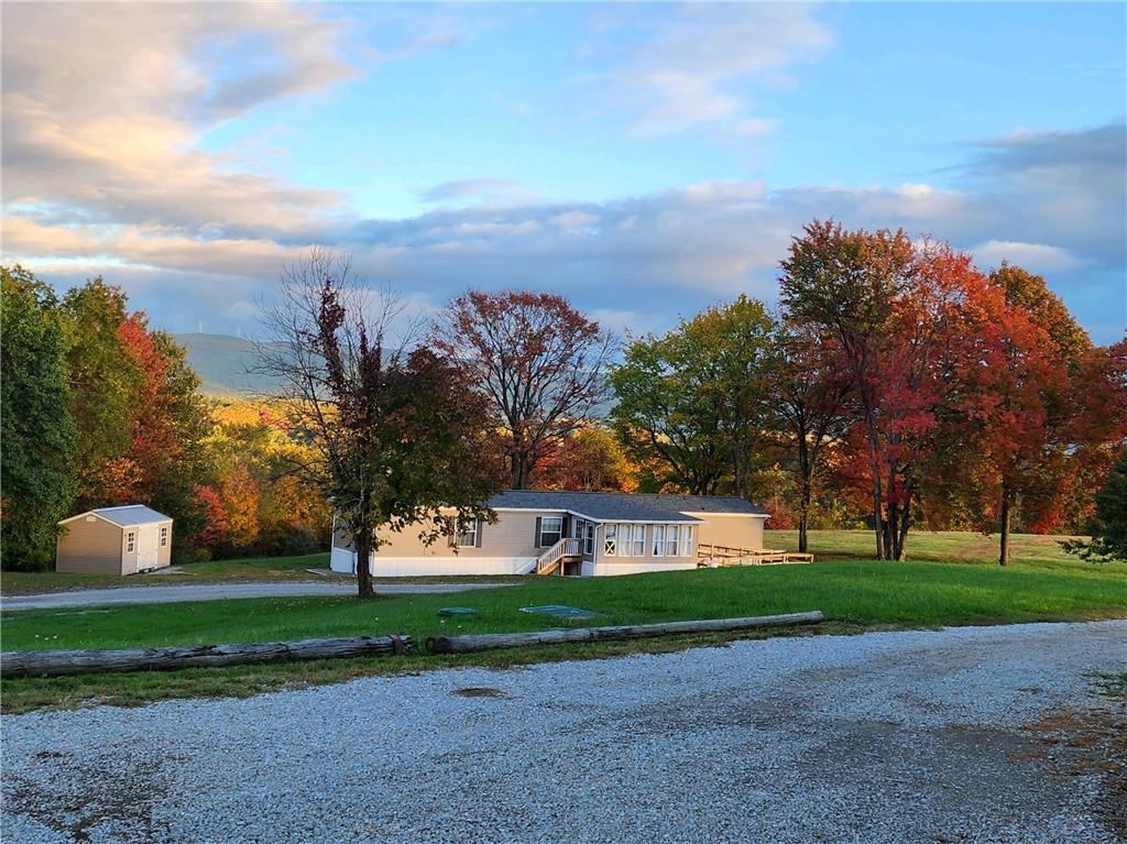 a view of a house with a big yard and large trees