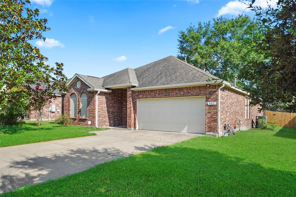 This is a single-story brick home with an arched entryway, two front-facing windows with decorative shutters, and an attached two-car garage. 