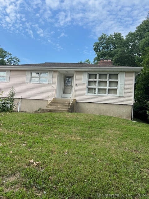 a front view of house with yard and trees in the background