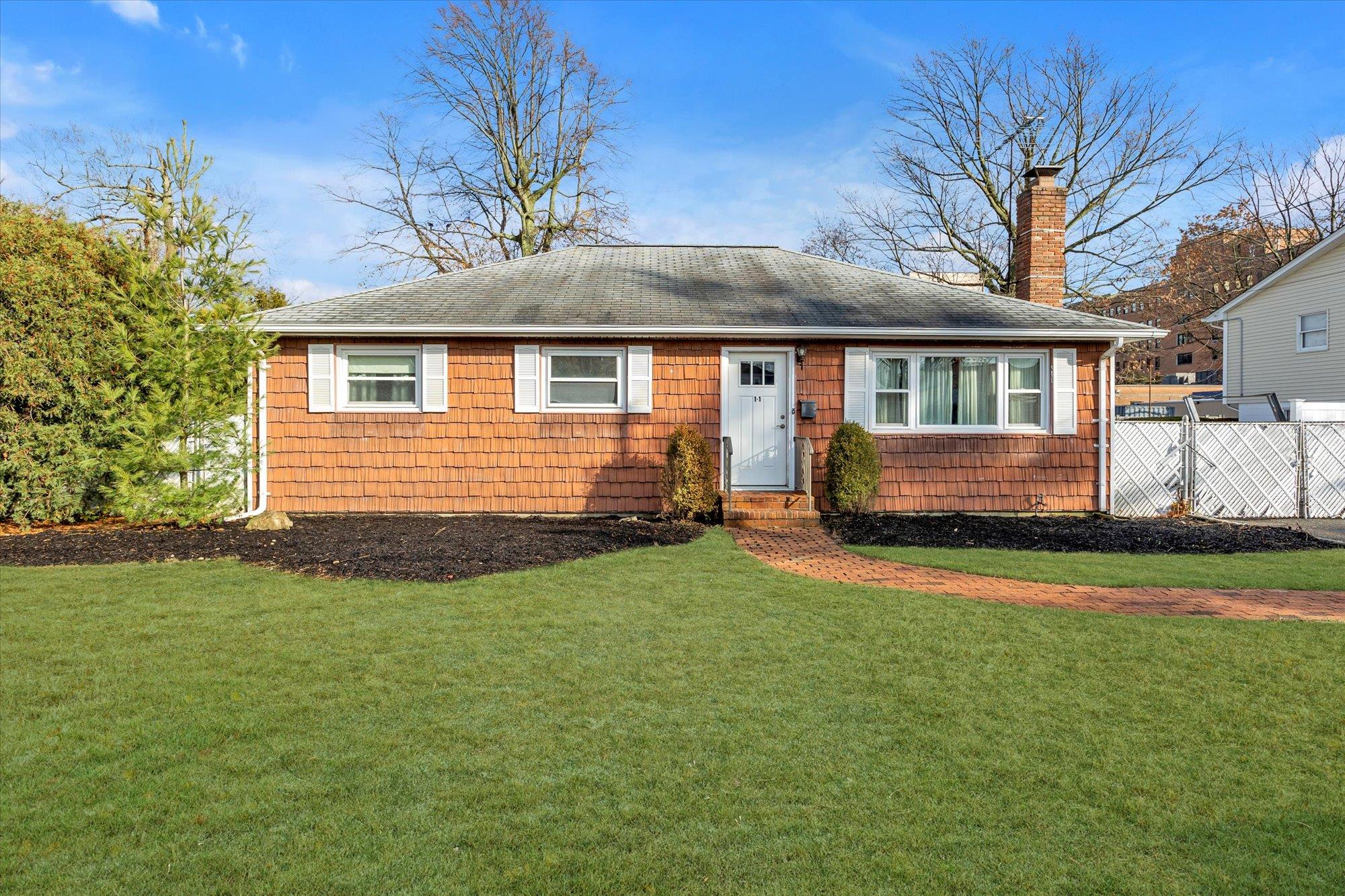 a front view of house with yard and trees in the background