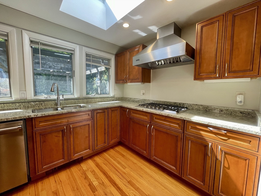 a kitchen with stainless steel appliances granite countertop wooden cabinets a sink and a large window