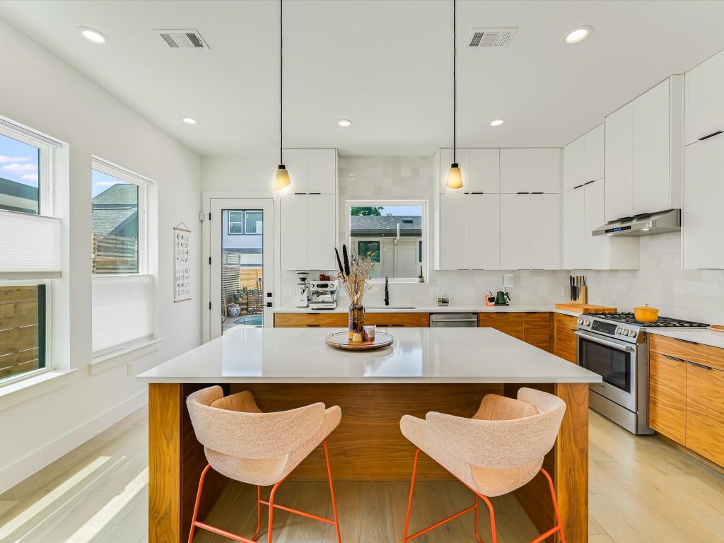 a kitchen with stainless steel appliances granite countertop a stove a sink a kitchen island with chairs and cabinets