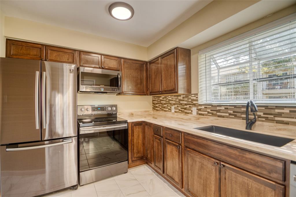 a kitchen with granite countertop a sink stainless steel appliances and window