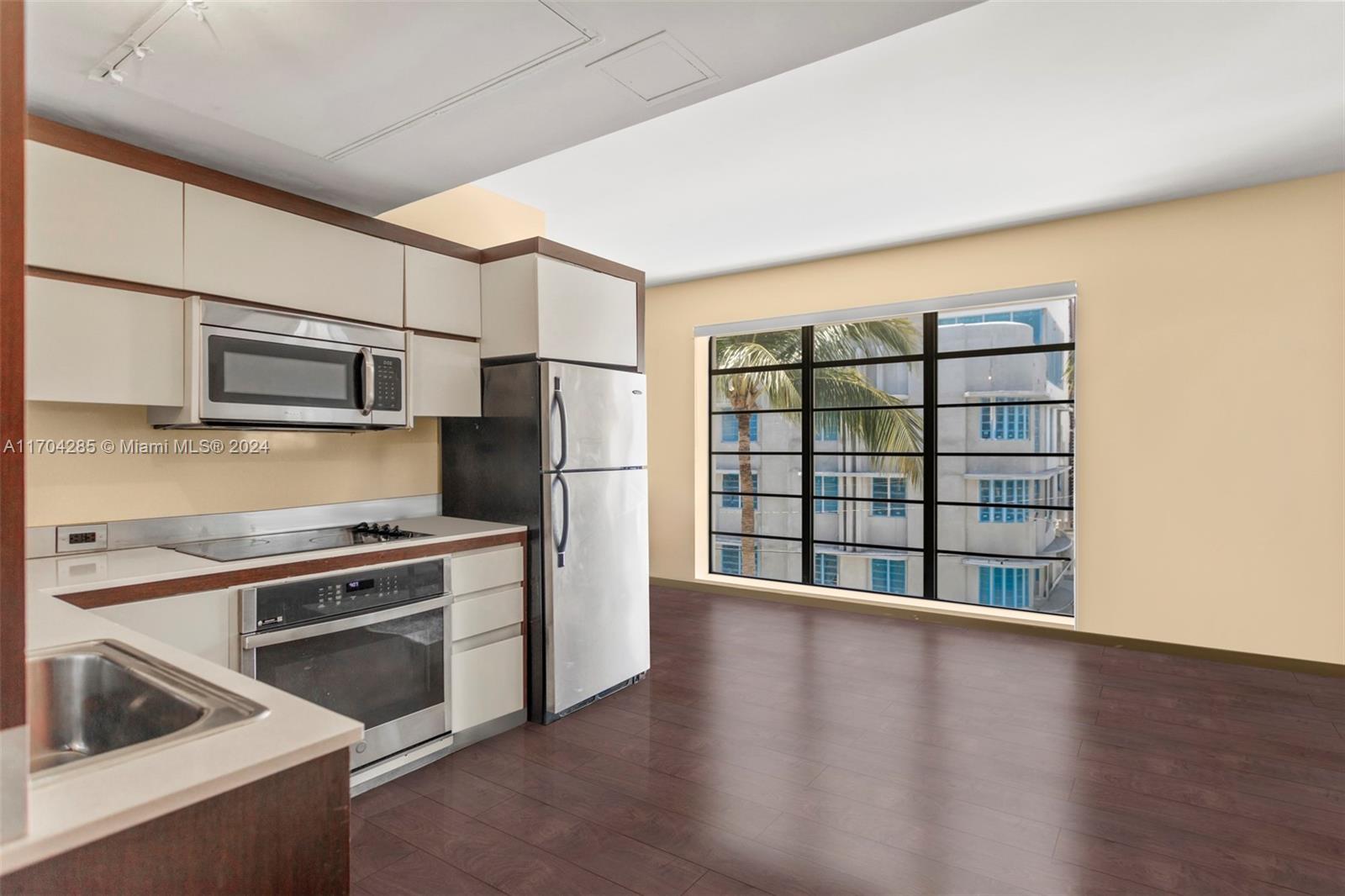 a view of a kitchen with a stove wooden cabinets and a refrigerator