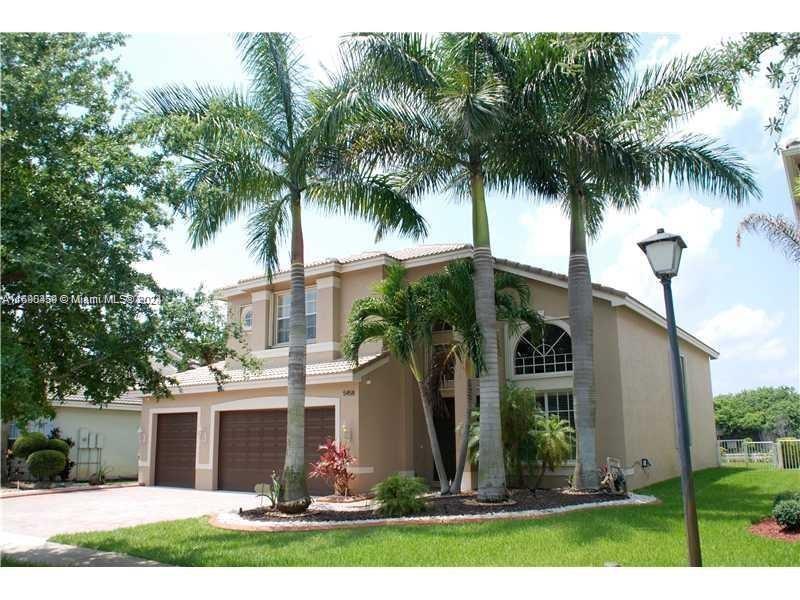 front view of house with a yard and palm trees