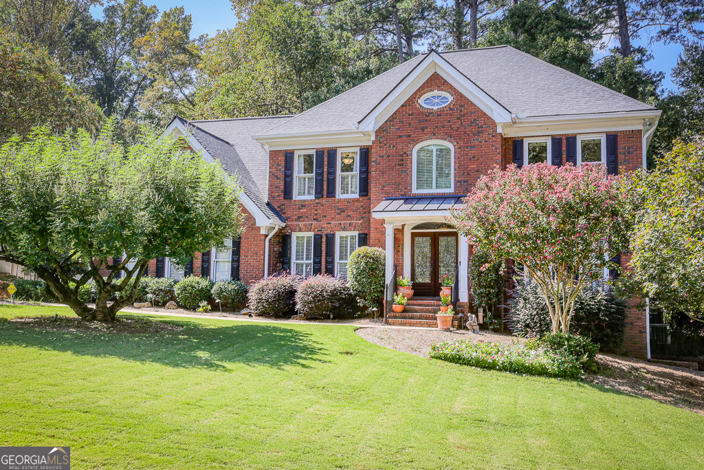 a front view of a house with garden and trees