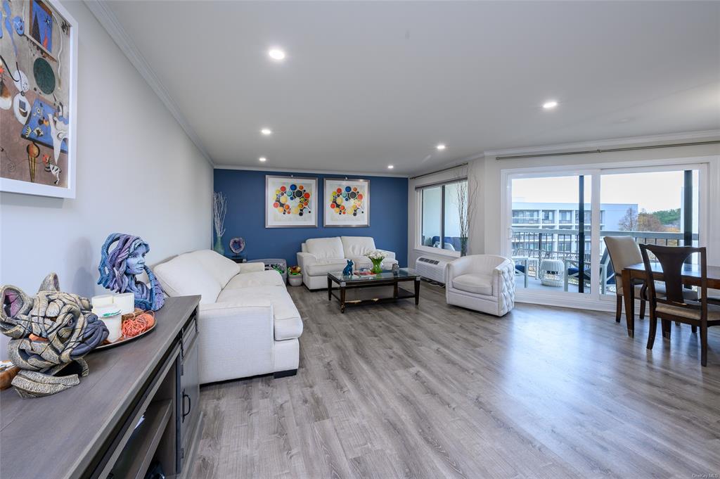 Living room featuring crown molding, a wall mounted AC, and light hardwood / wood-style flooring