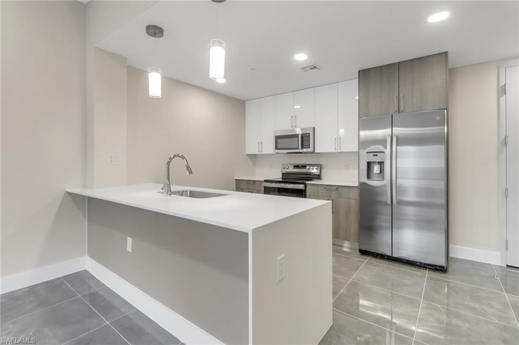 a kitchen with kitchen island a refrigerator sink and cabinets