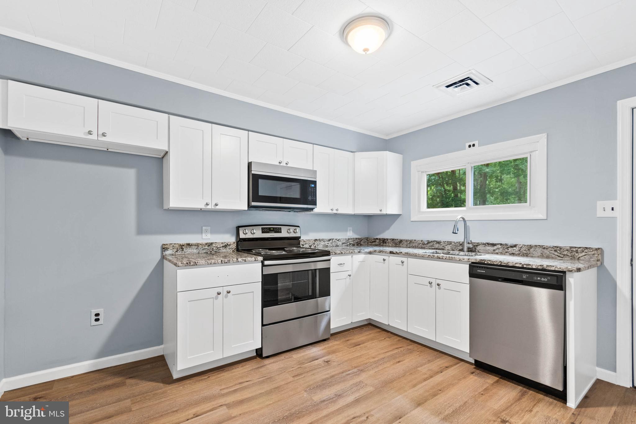 a kitchen with granite countertop white cabinets and appliances