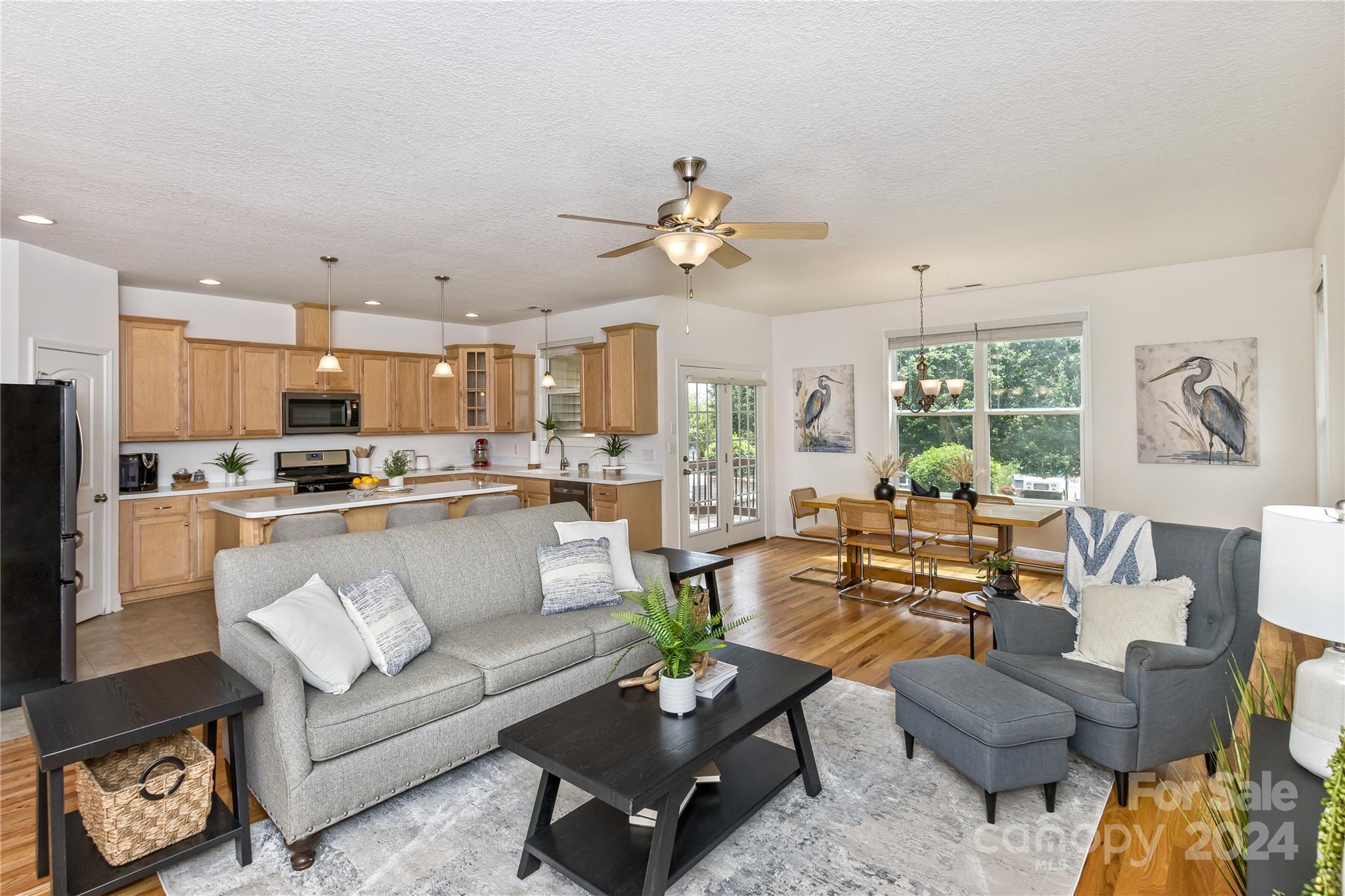 a living room with furniture kitchen view and a large window