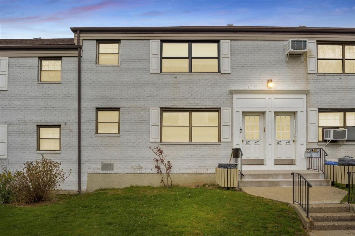 Back house at dusk with a wall mounted air conditioner, cooling unit, a yard, and french doors