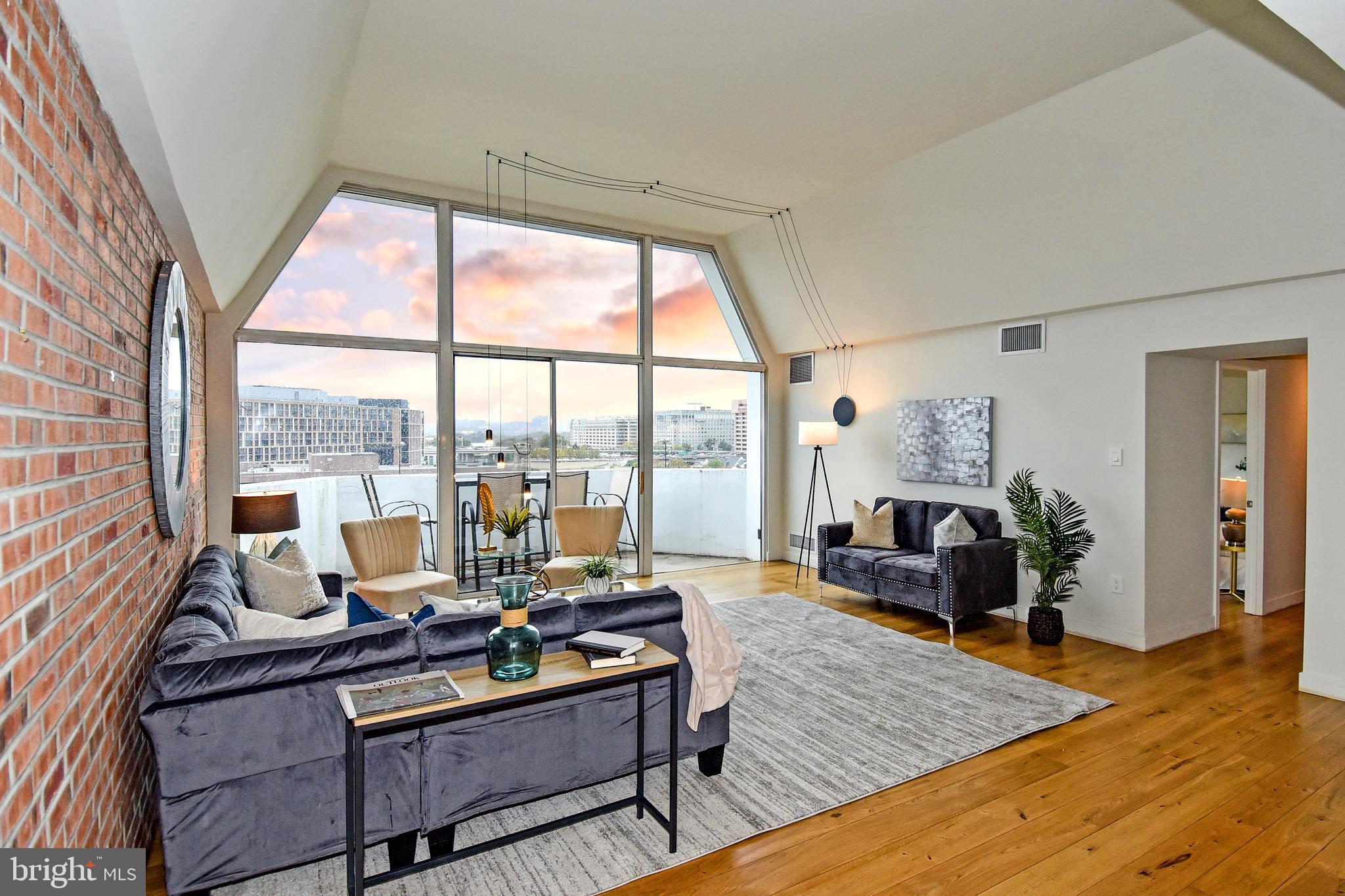 a living room with furniture large windows wooden floor and a table