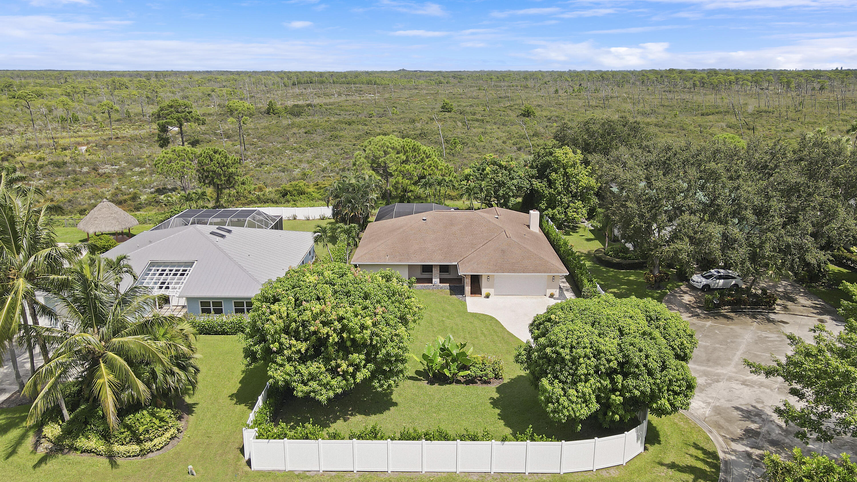 an aerial view of residential house with outdoor space and trees all around