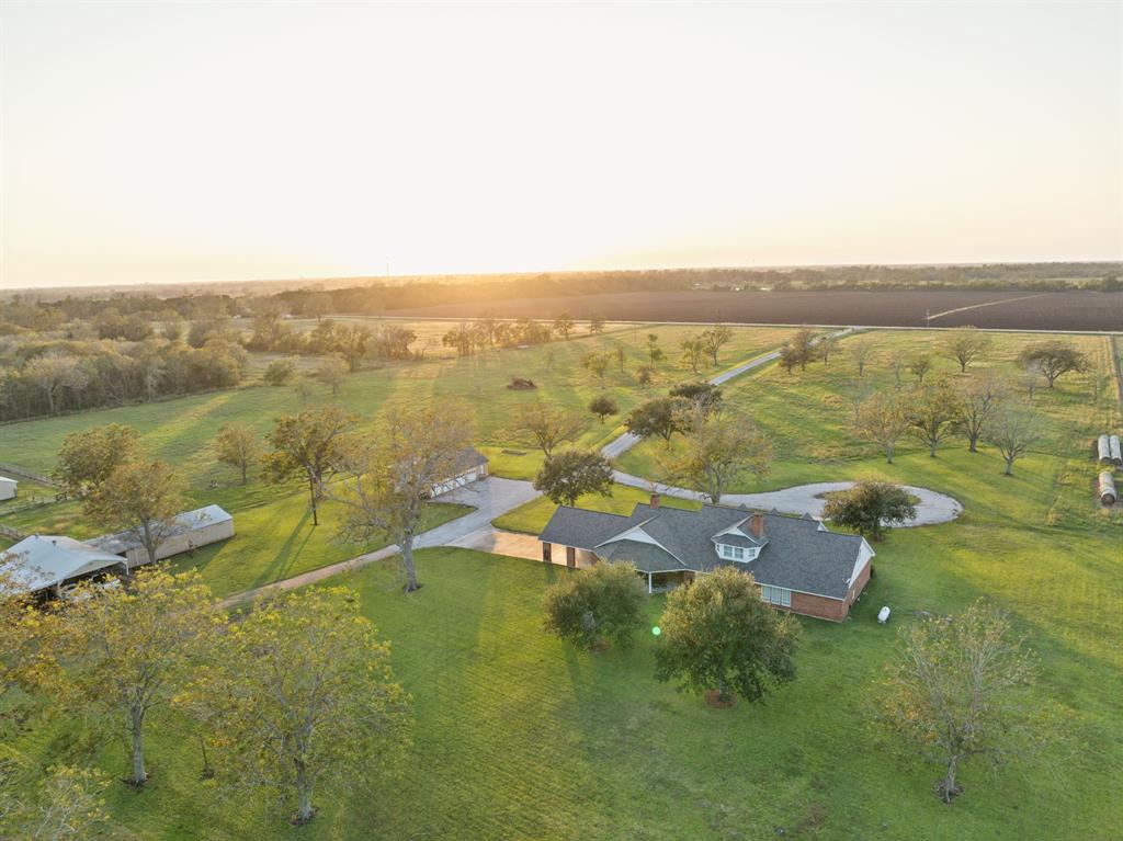 This breathtaking aerial view showcases the vast, open landscape of The Mary B Ranch, a 33-acre estate just north of Wharton, TX. Green fields and scattered trees create a peaceful country retreat, perfect for those seeking serenity.