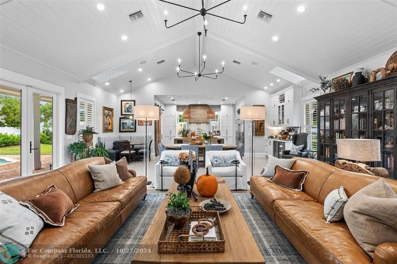 a living room with furniture kitchen view and a large window