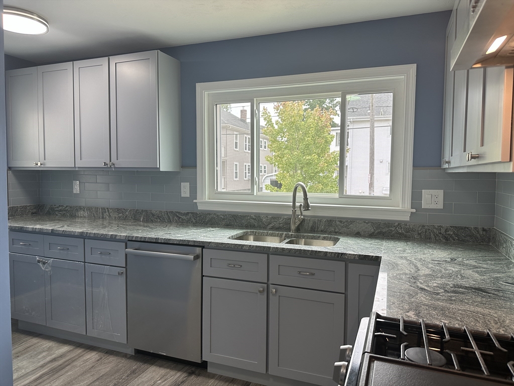 a kitchen with granite countertop a sink and white cabinets