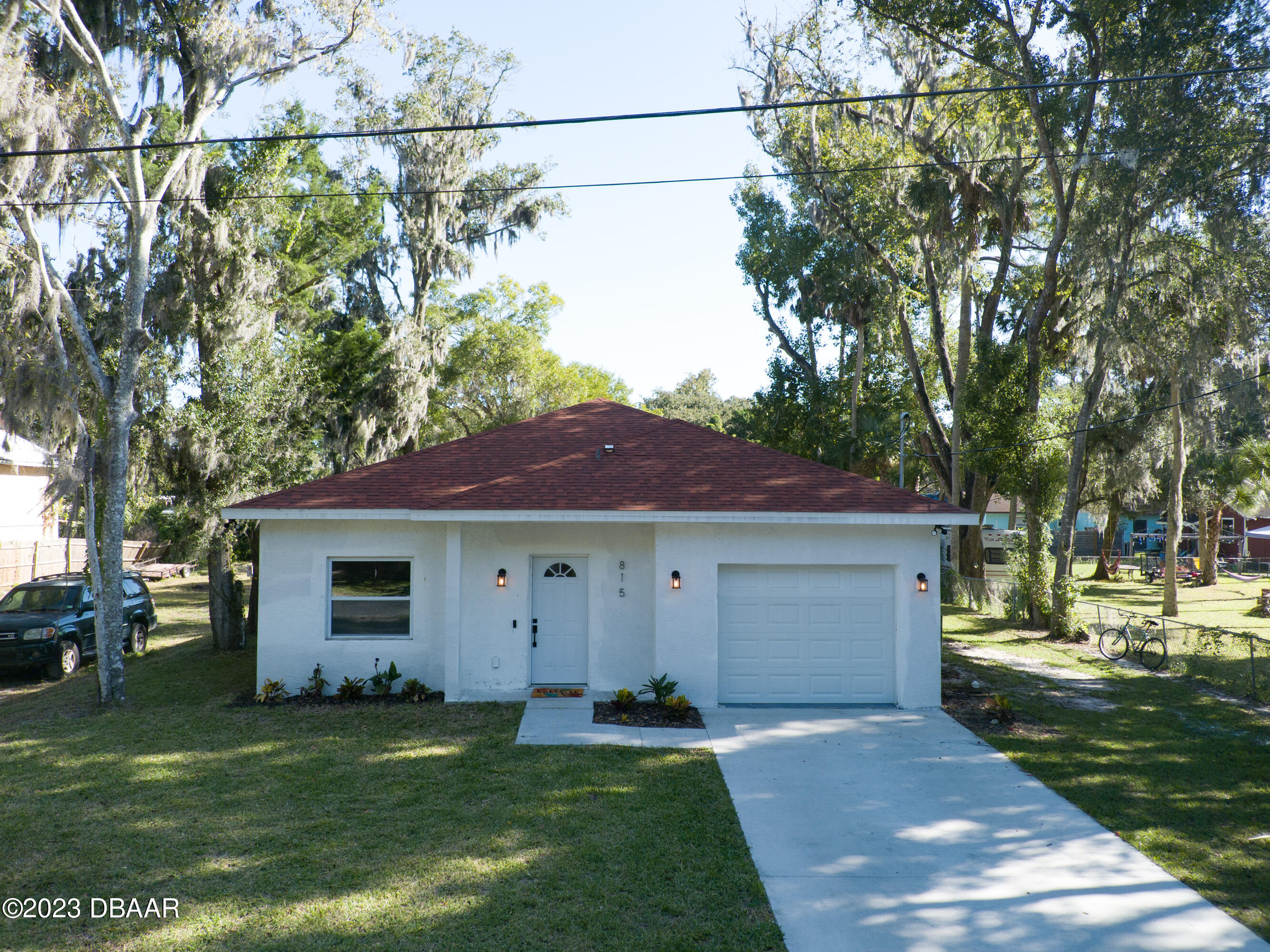 a front view of a house with a garden and trees