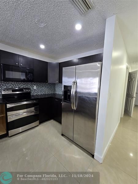 a kitchen with stainless steel appliances granite countertop a refrigerator and a stove