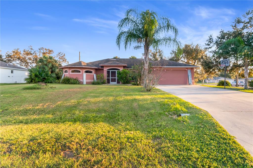 a front view of a house with a yard and palm trees