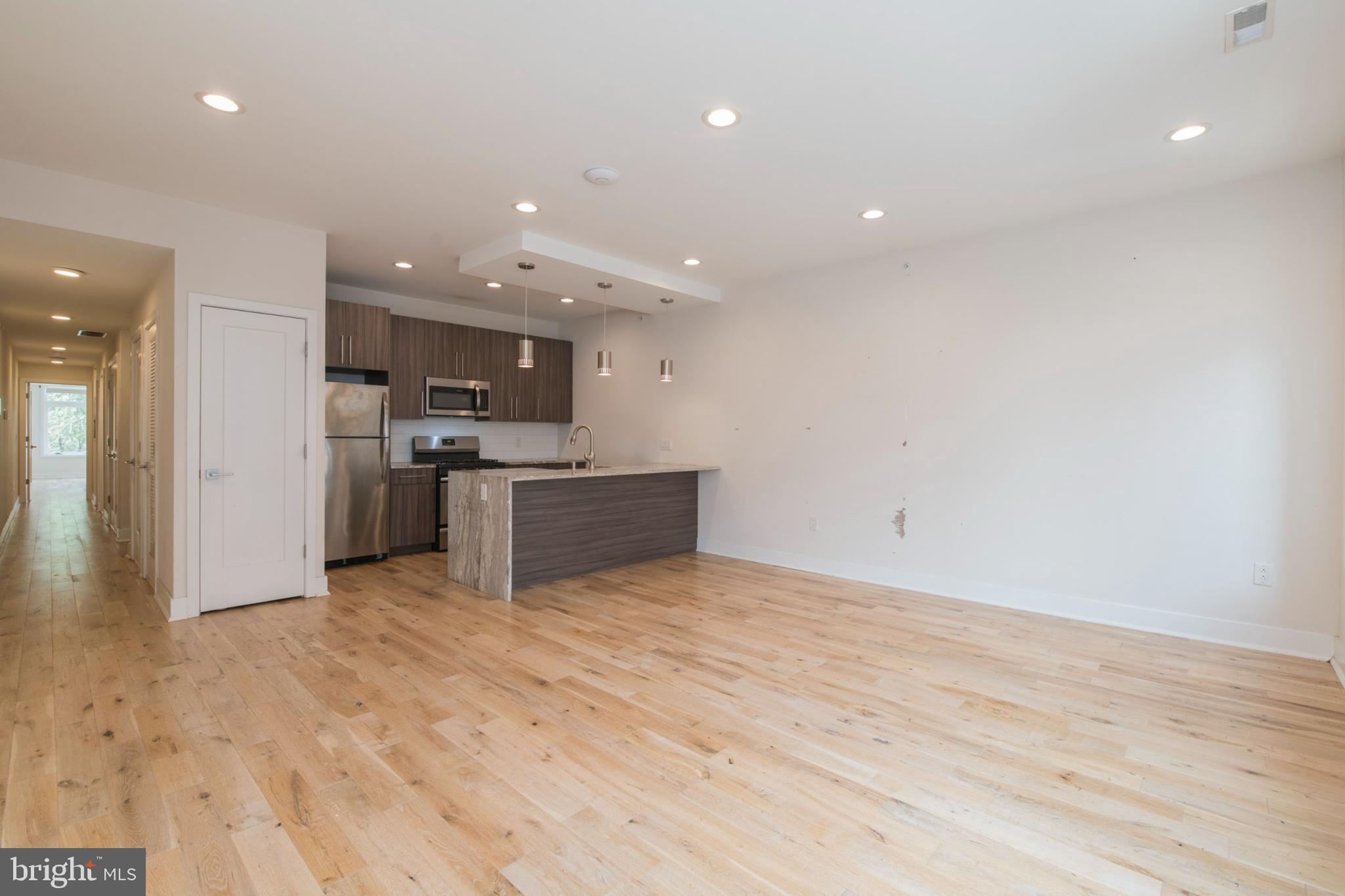 a view of kitchen with stainless steel appliances wooden floor and chandelier